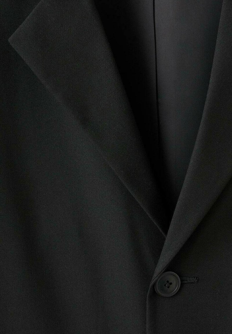 Blazer nero con colletto a revers, chiusura a un bottone, texture del tessuto liscia e struttura sartoriale con linee pulite.