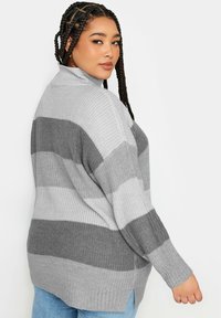 Grau gestreifter Pullover mit hohem Kragen, gerippter Textur und Seitenschlitzen. Lange Ärmel mit lockerer Passform, mit wechselnden dunkelgrauen und hellgrauen Streifen.