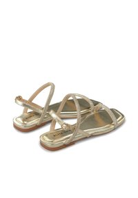Złote sandały na płaskiej podeszwie z cienkimi paskami, o błyszczącej metalicznej powłoce i dekoracyjnymi paskami na kostkę z małymi akcentami z metalu.
