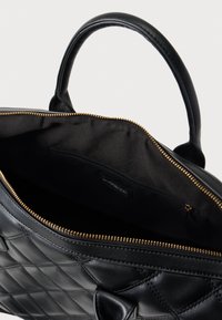 Μαύρη δερμάτινη γυναικεία τσάντα με σχέδιο καπιτονέ, χρυσρό φερμουάρ και χειρολαβές στο πάνω μέρος. Το εσωτερικό διαθέτει μαύρη επένδυση με τσέπη με φερμουάρ.