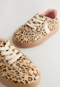 Sneakersi s uzorkom leoparda s gornjim dijelom nalik na teksturiranu krznu, kremasto obojenim vezicama i svijetlosmešanim gumiranim potplatom; mekana ružičasta obloga vidljiva unutra.