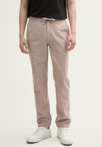 Lichtroze, getextureerde sweatpants met een elastische tailleband en trekkoord. Gecombineerd met witte sneakers, wat een casual ontwerp laat zien.