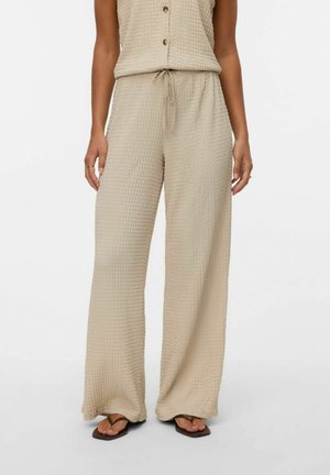 Pantalons beiges texturés avec une coupe ample et une taille élastique. Le tissu présente un motif tissé subtil pour une touche de détail supplémentaire.