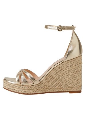 Sandalia cuña metálica dorada con tacón de yute trenzado, que presenta un diseño de banda ancha y hebilla en el tobillo. Textura suave y estilo de punta abierta.