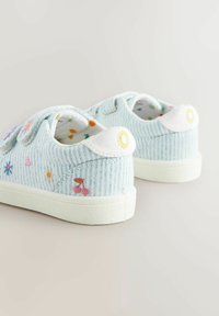 Des chaussures en velours côtelé bleu clair avec des semelles blanches, ornées de broderies colorées de fleurs et de fruits. Bandes Velcro pour un enfilage facile.