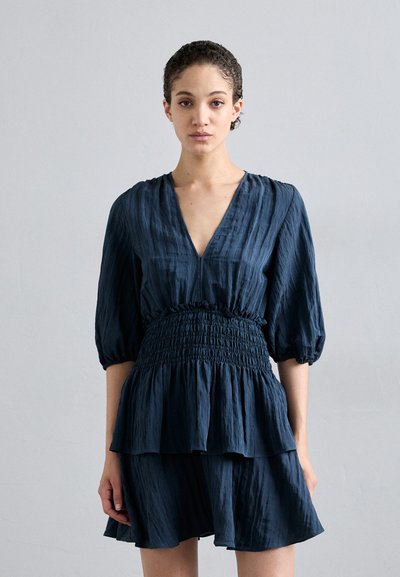 Navyblaues Kleid mit V-Ausschnitt, schmaler Taille und Puffärmeln, ausgestattet mit geschichteten Rüschen und einem strukturierten Stoff.