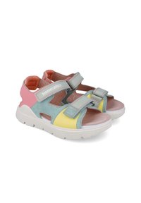 Sandalias infantiles coloridas con una mezcla de ante azul claro, rosa y amarillo, con correas ajustables y suela blanca.