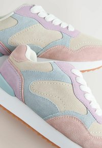 Suede sneakers in pastel colors: light blue, pale pink, and beige, with white laces and a textured sole. Rounded shape and stitched accents.