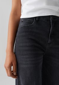 Zwarte denim jeans met een slim fit, voorzien van voorzakken, een metalen knoopsluiting en subtiele wassing op de stof.