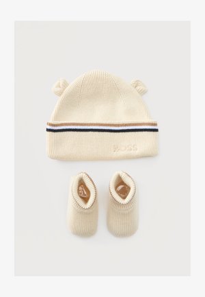 Flødefarvet strikket babyhue med små ører og matchende futter, med stribet kant og subtil præget branding.