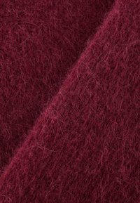 Bordeaux wollen stof met een zachte, fluffy textuur; heeft een losse weving met zichtbare vezels die diepte en warmte creëren.