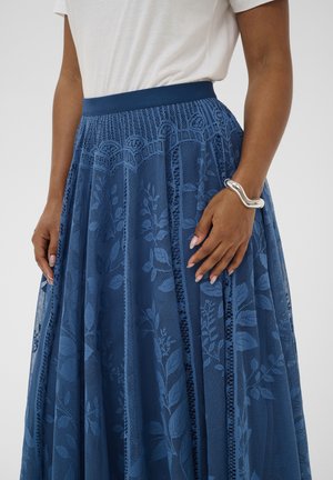 Blauer Spitzenrock mit floralem Muster, strukturiertem Design und elastischem Bund. Der Stoff ist halbtransparent mit vertikalen Details und elegantem Fall.