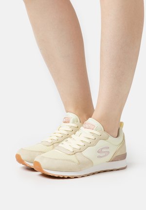 Light yellow sneakers with a textured upper, laces, and a subtle logo; features a cushioned sole and a beige accent on the heel.