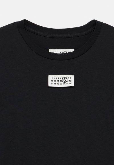 Čierne tričko s okrúhlym výstrihom, na ktorom je biela štítok s číslami a akcent grafiky v strede. Hladká bavlnená textúra.