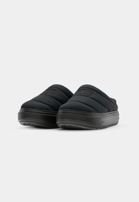 Sorte quiltede slip-on sko med en teksturert gummisåle og lav profil. Har en rektangulær lapp på overdelen med merkevare.