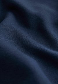 Tumesinine kangas, millel on sile, kergelt tekstuuriga pind, peened varjundite erinevused ja ühtlane kudumismuster.