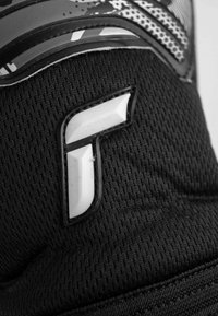 Tessuto nero con un logo bianco prominente inserito, con una finitura testurizzata e sottili modelli grafici in grigio.