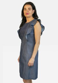 Vestido de mezclilla con mangas acampanadas, diseño ajustado, hasta la rodilla. Tela azul oscura, textura suave y costuras mínimas. Pulsera plateada en la muñeca.