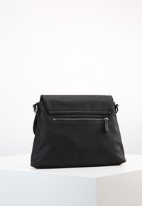 Černá kožená kabelka s texturovaným povrchem, uzavíráním na klopu a přední kapsou na zip. Disponuje jedním nastavitelným popruhem a minimalistickým designem.