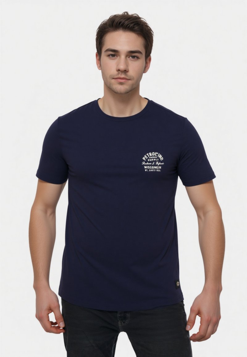Camiseta de color azul marino hecha de algodón, con cuello redondo y mangas cortas. Incluye texto del logo en blanco en el área del lado izquierdo del pecho.