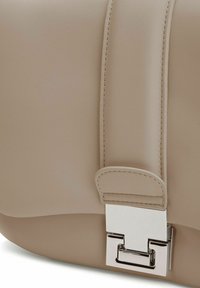 Beige leren tas met een gladde textuur, brede schouderriem en een rechthoekige zilveren metalen sluiting.