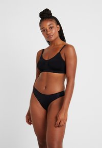 Μαύρο σουτιέν και αντίστοιχες μπικίνι βερμούδες, κομψός σχεδιασμός, μαλακό ύφασμα, ρυθμιζόμενοι ιμάντες, μινιμαλιστικό στυλ με διακριτική επωνυμία.