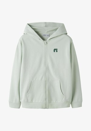 Šviesiai pilka hoodie su užtrauktuku, priekinėmis kišenėmis, ribuotais rankogaliais ir apačia, mažu tamsiu logotipu ant kairės krūtinės ir gaubtu.