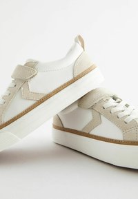 Baskets blanches avec une combinaison de cuir lisse et d'accents en suédine beige. Design low-top avec lacets plats et semelles en caoutchouc texturé.
