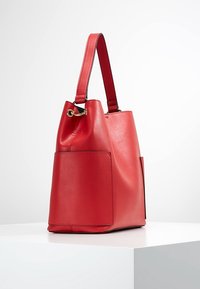 Červená kožená taška se strukturovaným tvarem, obsahující plochou boční kapsu, zlaté kování a jeden nastavitelný popruh. Hladký povrch.