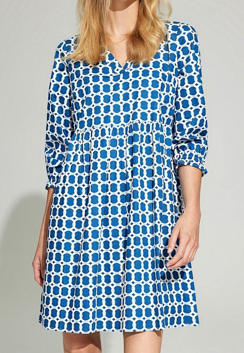 Blau-weiß gemustertes Kleid mit V-Ausschnitt, Dreiviertelärmeln und gerafftem Taillenbund. Hergestellt aus leichtem Stoff mit geometrischem Design.