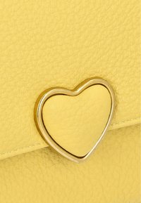 Geantă din piele texturată galbenă, cu un accent metalic în formă de inimă de culoare aurie. Designul evidențiază un finisaj elegant și neted.