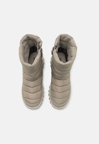 Beige Isolierstiefel mit gestepptem Design, gepolstertem Schaft, seitlichen Reißverschlüssen und Gummisohlen, die sich für den Außenbereich eignen.