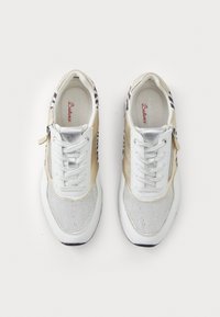 Baskets blanches et beiges avec embouts pailletés argentés, fermetures éclair latérales et accents au talon à motif zèbre, vues de dessus sur fond blanc.