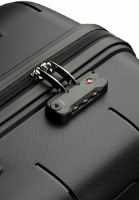 Black hard-shell suitcase features a textured surface, dual zippers, and a TSA-approved lock with red accent.