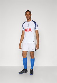 Hvid fodboldtrøje med marineblå accenter, rød "AIA" logo, parret med hvide shorts og blå sokker. Sorte og blå støvler. Nike-branding.