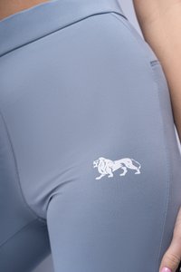 Leggings atletici grigio chiaro con una texture liscia, dotati di un logo di leone bianco sulla coscia superiore e un design a vita alta.