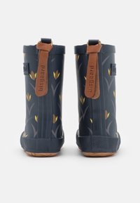 Bottes de pluie en caoutchouc navy avec un motif floral jaune, semelle texturée, et accents en cuir brun sur la tige et le talon pour un enfilage facile.