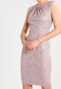 Robe en dentelle d'un lavender doux avec des détails en sequins. Design ajusté et sans manches, avec un col froncé. Texture lisse.