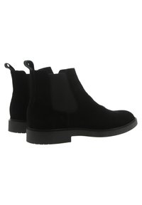 Bottines Chelsea en cuir suede noir avec panneaux élastiques sur les côtés, bout rond et tirettes, dotées d'une semelle en caoutchouc texturé pour une meilleure adhérence.