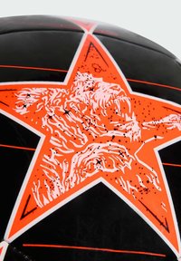 Pallone da calcio nero con un disegno a stella arancione che presenta la testa di un leone. Accentuato da contorni bianchi e linee rosse sulla superficie.