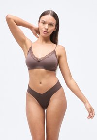 Καφέ μπραλέτα με δαντέλα, συνδυασμένη με καφέ εσώρουχο ψηλής μέσης. Μαλακό ύφασμα, χωρίς ραφές, με V-σχήμιο κόψιμο στη ζώνη μέσης.