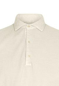 Polo de color beige claro, hecho de una tela texturizada, con cuello tipo puntiagudo y una tapeta de tres botones con botones claros a juego.