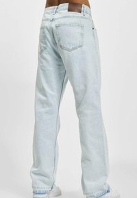 Lysblå denim jeans med en afslappet pasform, fem lommer, et læder bagpatch og kontrastfuld syning. Glat tekstur, bred benåbning.