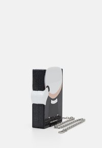 Czarna błyszcząca prostokątna torebka z rysunkowym wizerunkiem mężczyzny w czarnym garniturze i białymi włosami, przypięta do srebrnego łańcucha.