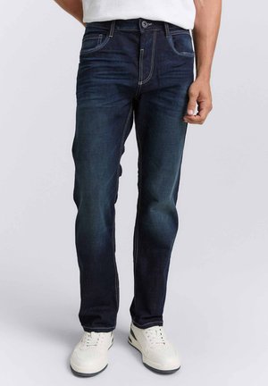 Donkerblauwe denim jeans met een recht model, voorzien van contrasterende stiksels, vijf zakken en een klassieke knoopsluiting. Draagt gecombineerd met witte sneakers.