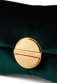 Pochette en velours vert avec un fermoir doré circulaire portant le nom gravé "Borbonese." Texture lisse, design élégant et tissu moelleux.