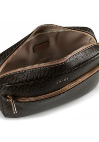 Bruine cosmetische tas met textuur en een goudkleurige rits, voorzien van een logo aan de voorkant en een gladde binnenvoering.