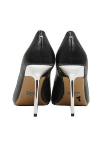 Escarpins en cuir noir à talons aiguilles argentés vus de dos sur un fond blanc.