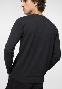Ciemnoszary sweter typu pulower z długimi rękawami, ściągaczami przy rękawach i u dołu oraz gładką fakturą. Posiada klasyczny okrągły dekolt i dopasowany krój.