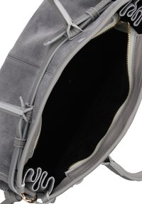 Borsa in suede grigio con chiusura a zip e fodera in tessuto morbido. Presenta decorativi dettagli con lacci e una tasca interna con finitura liscia.
